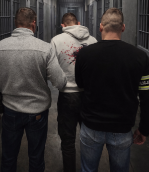 Policjanci prowadzą zatrzymanego mężczyznę.