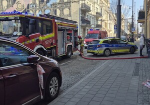 Radiowozy policyjne i straży pożarnej przed kamienicą.