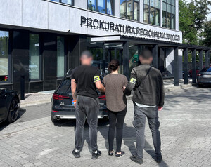 Policjanci z zatrzymaną kobietą przed Prokuraturą Regionalną w Łodzi.