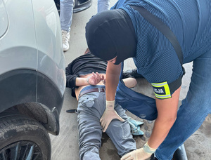 Policjanci zatrzymują złodzieja auta na stacji paliw.