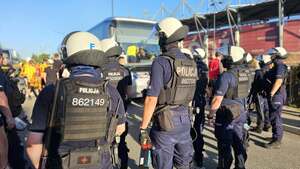 Policjanci zabezpieczają przejście kibiców drużyny przyjezdnej na stadion.