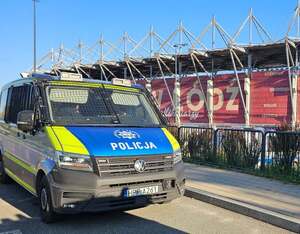Radiowóz policyjny na tle stadionu.