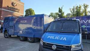 Policyjny radiowóz i armatka wodna pod stadionem.