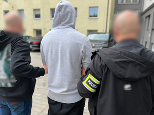 Policjanci prowadzą zatrzymanego mężczyznę.