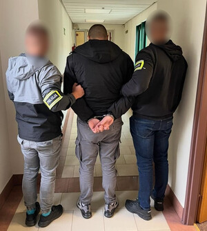Policjanci prowadzą zatrzymanego mężczyznę.