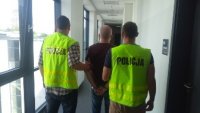 Na zdjęciu widać dwóch policjantów po cywilnemu ubranych w kamizelki z napisem policja pomiędzy nimi stoi mężczyzna - sprawca zdarzenia.