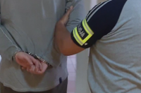 napis policja na ramieniu policjanta prowadzącego zatrzymanego