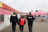 Policja, Straż Miejska i pracownik Powiatowej Stacji Sanitarno-Epidemiologicznej w Skierniewicach kontrolują targowisko miejskie, przechodzą pomiędzy straganami