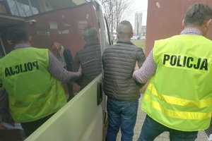 Mężczyzna i policjant w kamizelce z napisem policja przy samochodzie