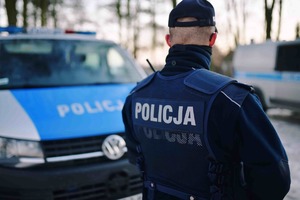 Policjant w mundurze na tle radiowozu