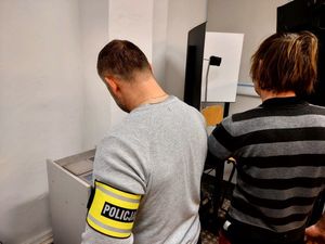 Policjant z opaską na ręku z napisem policja i mężczyzna podczas pobierania odcisków palców.