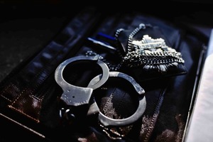 Kajdanki i odznaka policyjna leżą na aktówce.