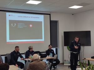 Uczestnicy i policjanci w sali.