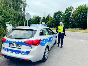 Policjantka ruchu drogowego stojąca rzy radiowozie.
