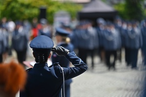 Policjantka oddająca honor do flagi państwowej.