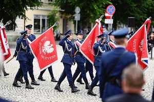 Policjanci ze sztandarami podczas przemarszu.