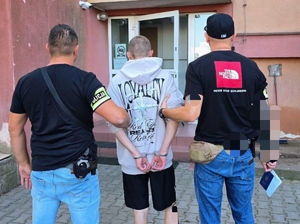 Policjanci przed komendą podczas doprowadzenia.