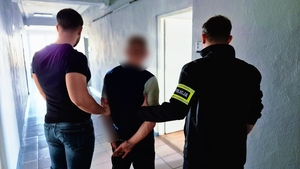 Policjanci z zatrzymanym podczas doprowadzenia.