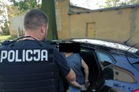 policja Skierniewice - osoba zatrzymana za rozbój wsiada do samochodu doprowadzana przez policjanta