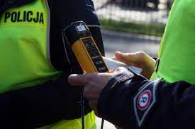 Policjant trzyma urządzenie do pomiaru trzeźwości.