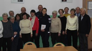 Stoi grupa seniorów i policjant z policjantką.