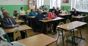 W sali szkolnej policjanci przeprowadzają pogadankę z seniorami.