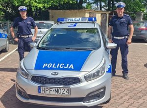 Dwóch policjantów przy radiowozie.