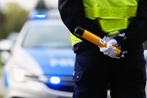 Na zdjęciu policjant, w tle radiowóz.