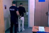 Policjant wprowadza zatrzymanego mężczyznę do pomieszczenia dla osób zatrzymanych pabianickiej komendy