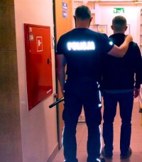 policjant wprowadza zatrzymanego mężczyznę do pomieszczenia dla osób zatrzymanych pabianickiej komendy