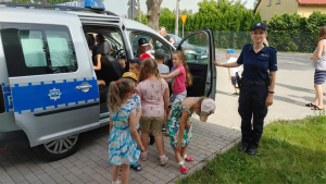 policjanta pokazuje przedszkolakom wnętrze radiowozu policyjnego