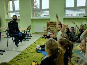 Policjantka siedzi na krześle, naprzeciwko niej znajdują się dzieci.