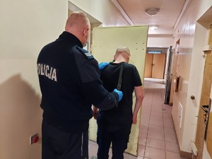 Policjant stoi z zatrzymanym mężczyzną.