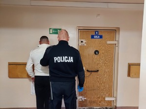 Policjant stoi z zatrzymanym mężczyzną.