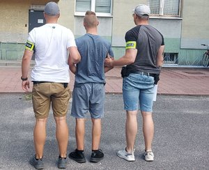 Dwóch nieumundurowanych policjantów prowadzi zatrzymanego.