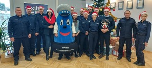 Wspólne zdjęcie, na którym widać policjantów, włodarzy powiatu i maskotkę garnizonu łódzkiego w czerwonych czapkach z białymi pomponami.