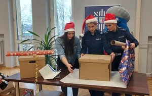 Policjantki i pracownik cywilny Policji pakują prezent.