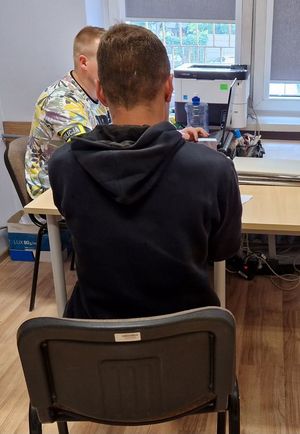 Zatrzymany mężczyzna przesłuchiwany przez nieumundurowanego policjanta.