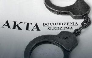 Zdjęcie dekoracyjne, przedstawiające kajdanki leżące na teczce z napisem akta dochodzenia śledztwa.