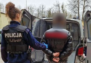 Umundurowana policjantka stoi z zatrzymanym mężczyzną.