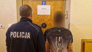 Policjant stoi z zatrzymanym mężczyzną.