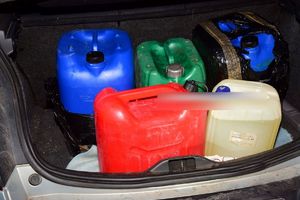 Kolorowe pojemniki z benzyną znajdujące się w bagażniku pojazdu.