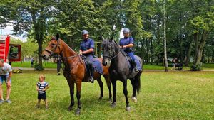 Dwa służbowe konie, na których siedzą policyjni jeźdźcy.