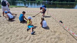 Dzieci szukają skarbów w piasku specjalnymi wykrywaczami.