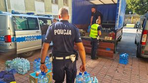 Policjanci wnoszący zebrane dary do pojazdów.