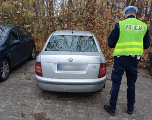 Policjant wykonujący oględziny samochodu.