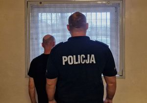 Policjant stoi z zatrzymanym mężczyzną.