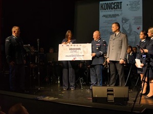 Na scenie policjanci i przedstawicielka fundacji. Kobieta odbiera czek z kwotą 2260 złotych