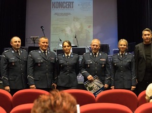 Umundurowani policjanci i policjantki pozują do wspólnego zdjęcia z Prezesem Stowarzyszenia Rodzina Policyjna 1939 roku w Łodzi. W tle widać plakat wydarzenia.