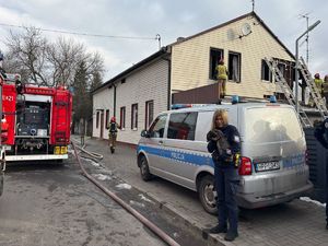 Policjantka stoi na tle radiowozu i wozu strażackiego. W rękach trzyma królika.